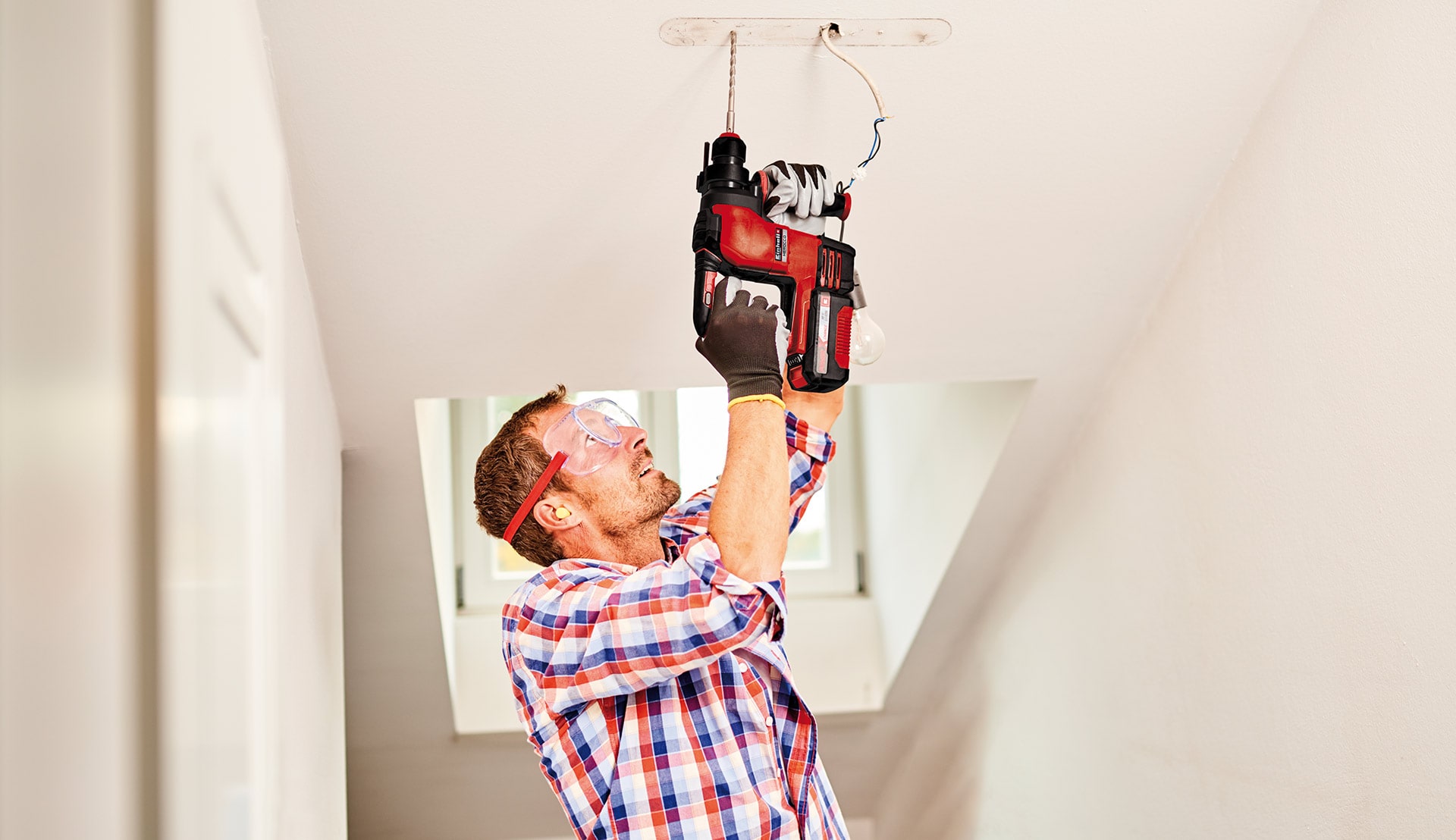 A man drills a hole in the ceiling